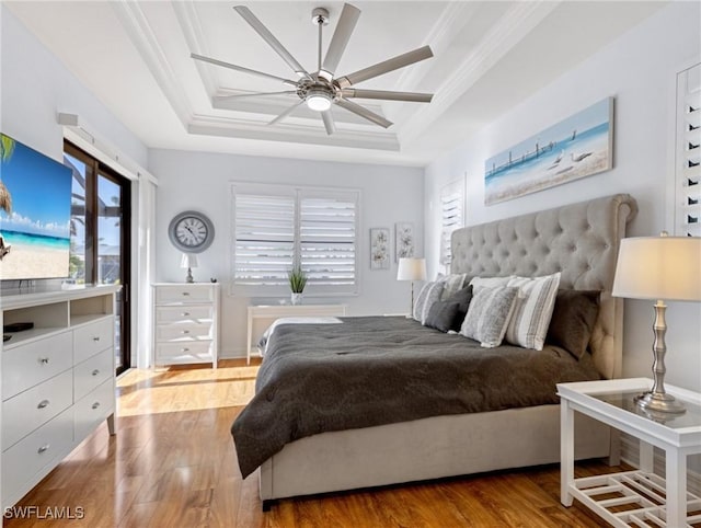 bedroom featuring light hardwood / wood-style flooring, a raised ceiling, ceiling fan, and crown molding