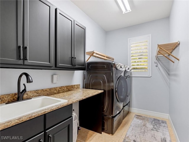 clothes washing area with cabinets, light tile patterned floors, washer and dryer, and sink