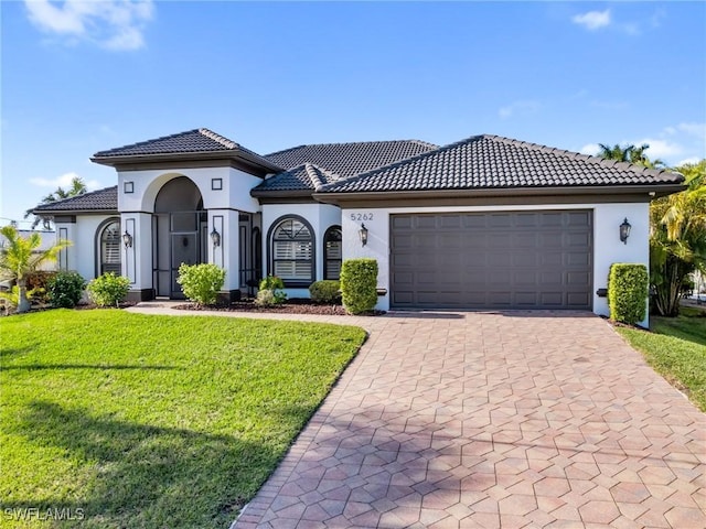 mediterranean / spanish house featuring a front yard and a garage