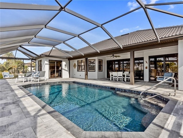 view of pool featuring glass enclosure, ceiling fan, and a patio