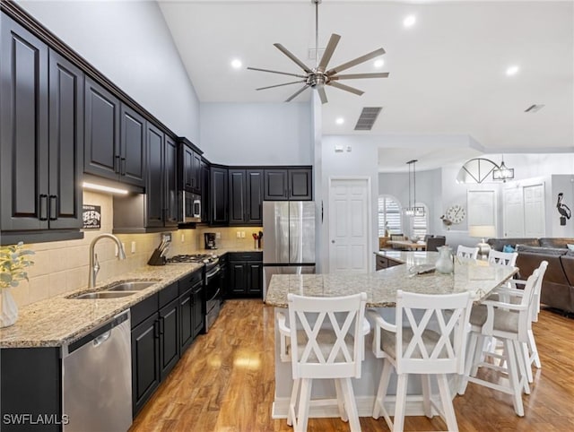 kitchen with appliances with stainless steel finishes, sink, pendant lighting, a center island, and a breakfast bar area