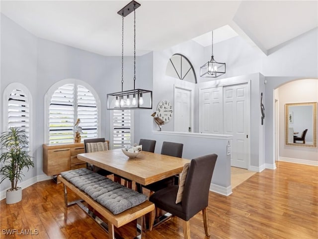 dining area with a high ceiling and light hardwood / wood-style flooring