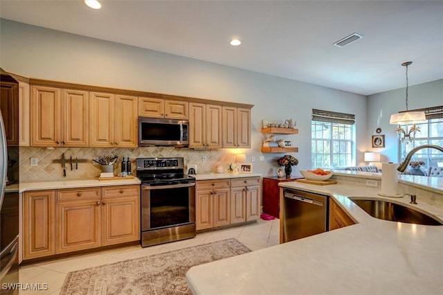 kitchen featuring sink, backsplash, decorative light fixtures, light tile patterned flooring, and appliances with stainless steel finishes