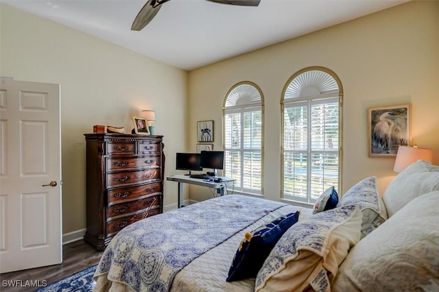 bedroom with ceiling fan, dark wood-type flooring, and multiple windows