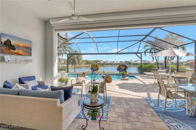 view of patio featuring glass enclosure, ceiling fan, a water view, and an outdoor living space