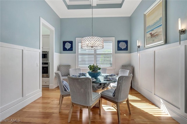 dining area with ornamental molding, light hardwood / wood-style flooring, and a notable chandelier