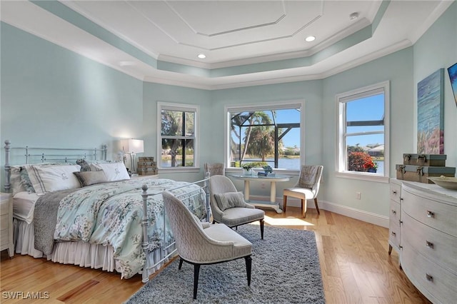 bedroom featuring light hardwood / wood-style floors, a raised ceiling, and ornamental molding