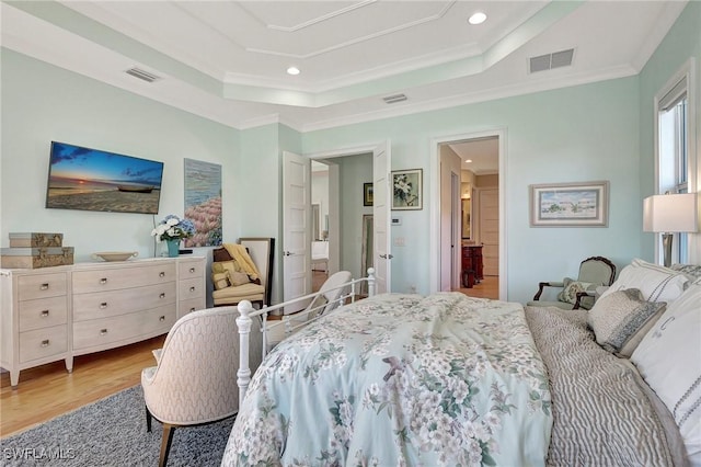 bedroom with a tray ceiling, light hardwood / wood-style flooring, and ornamental molding