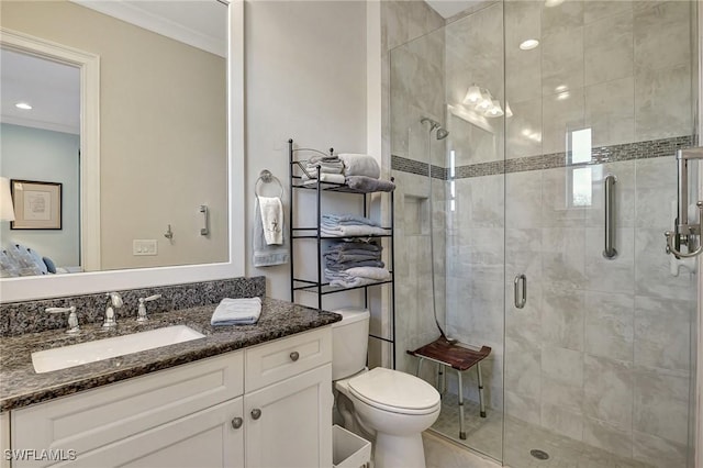 bathroom with toilet, vanity, crown molding, and a shower with shower door