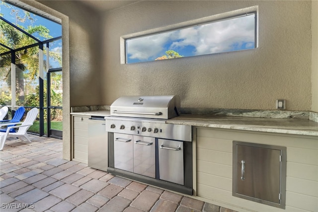 view of patio / terrace with glass enclosure, a grill, and an outdoor kitchen