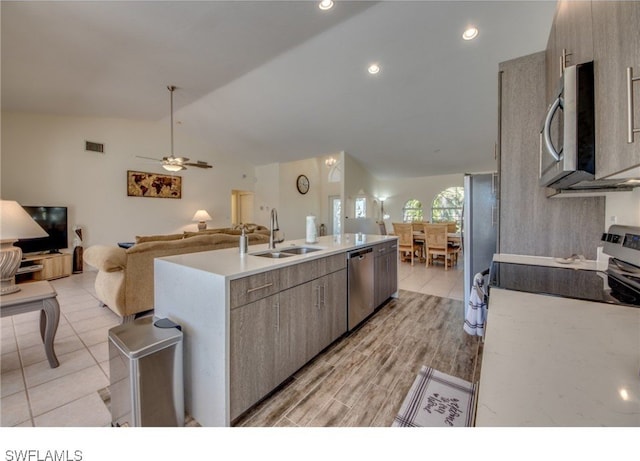 kitchen featuring ceiling fan, sink, stainless steel appliances, lofted ceiling, and a kitchen island with sink