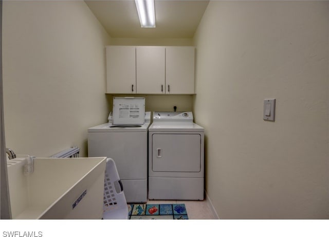 clothes washing area featuring light tile patterned flooring, cabinets, and separate washer and dryer