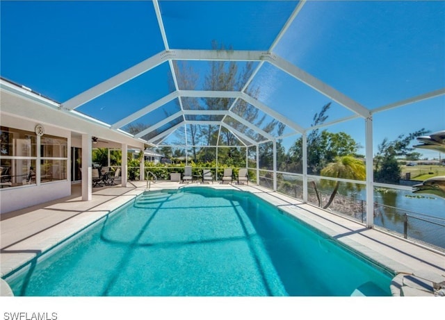 view of pool with glass enclosure, a water view, and a patio