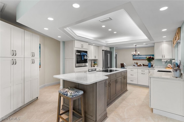 kitchen featuring white cabinetry, sink, stainless steel appliances, a raised ceiling, and a kitchen island