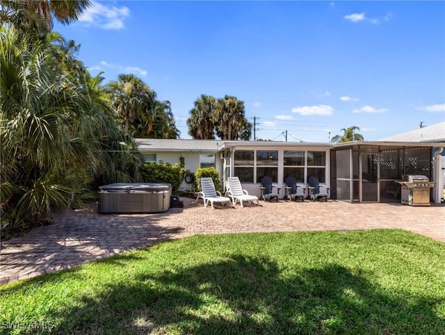 rear view of property with a lawn, a patio area, a sunroom, and a hot tub