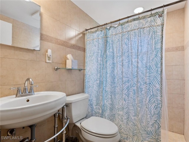 bathroom with sink, a shower with curtain, toilet, and tile walls