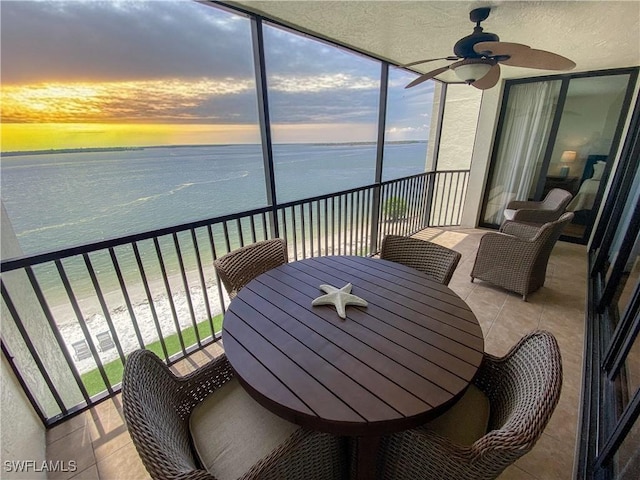 sunroom / solarium with a beach view, a water view, and ceiling fan