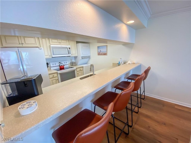 kitchen featuring crown molding, sink, electric stove, cream cabinetry, and a breakfast bar area