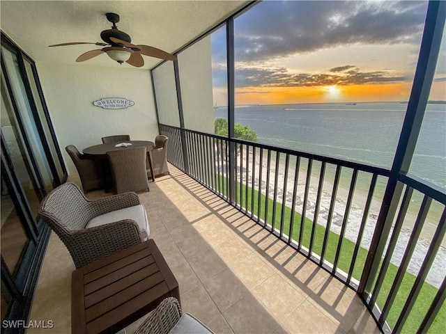 sunroom featuring a beach view, a water view, and ceiling fan