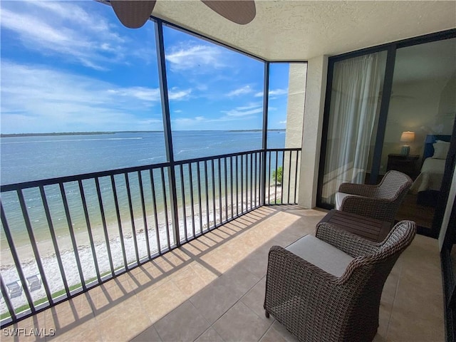 sunroom / solarium with ceiling fan, a water view, and a beach view