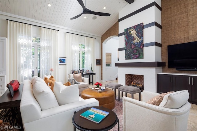 living room featuring beam ceiling, ceiling fan, wooden ceiling, high vaulted ceiling, and a fireplace