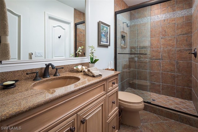 bathroom with an enclosed shower, vanity, toilet, and tile patterned floors