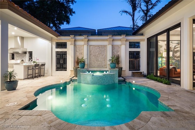 view of swimming pool with an in ground hot tub, an outdoor kitchen, area for grilling, exterior bar, and a patio area