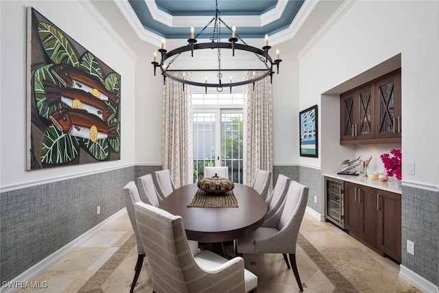 dining space featuring a tray ceiling, an inviting chandelier, beverage cooler, and ornamental molding