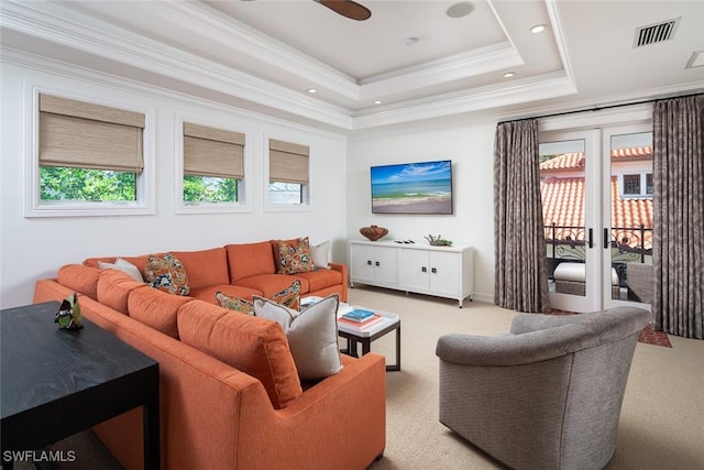 living room with a tray ceiling, ceiling fan, carpet flooring, and ornamental molding