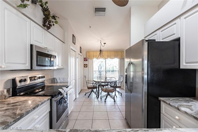 kitchen featuring decorative light fixtures, white cabinetry, stainless steel appliances, and light tile patterned floors