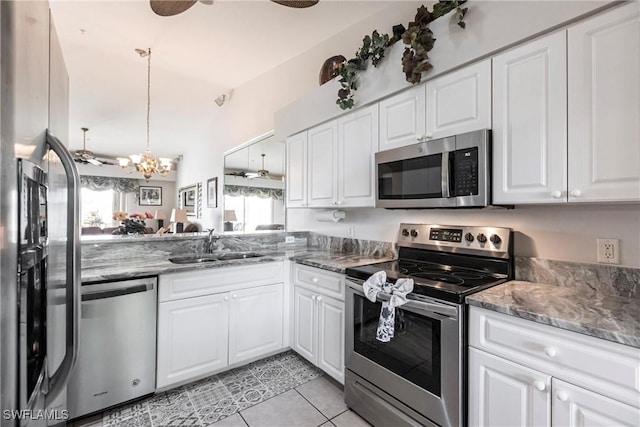 kitchen with sink, stainless steel appliances, light tile patterned floors, a notable chandelier, and white cabinets