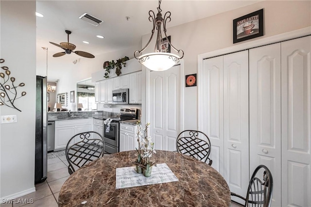 tiled dining room with ceiling fan and sink