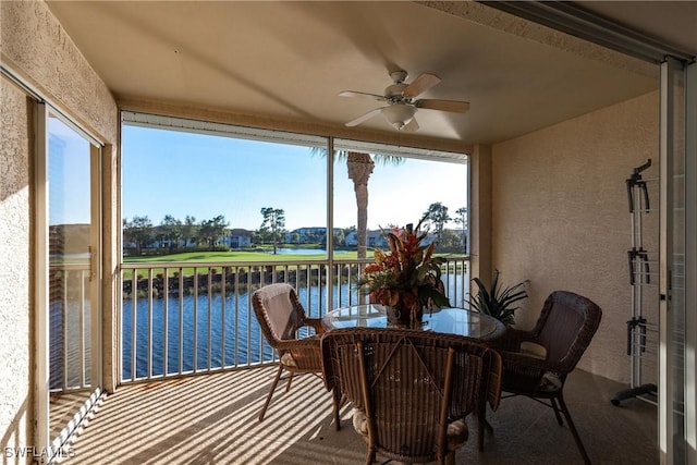 sunroom / solarium featuring ceiling fan and a water view