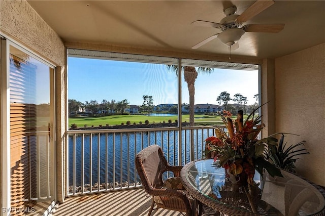 sunroom / solarium with a wealth of natural light, ceiling fan, and a water view