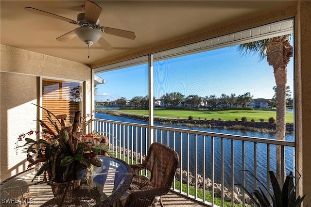 sunroom / solarium with ceiling fan and a water view