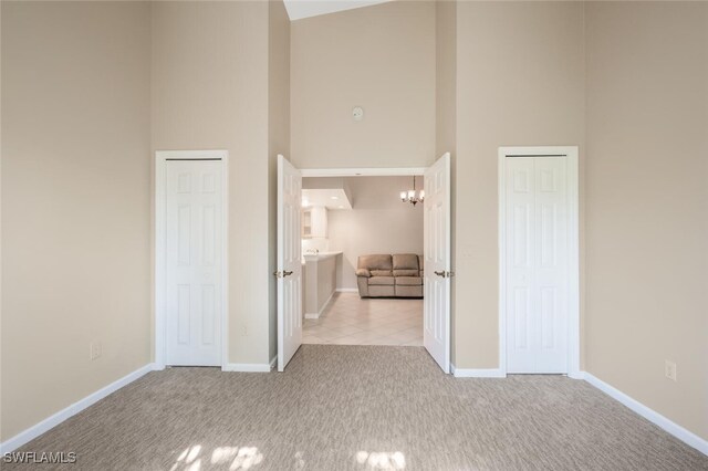 interior space with a towering ceiling, an inviting chandelier, and light carpet