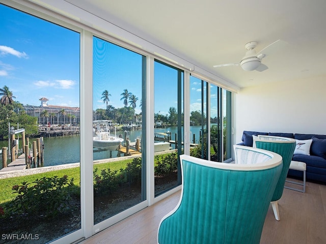 sunroom featuring ceiling fan, a water view, and a healthy amount of sunlight