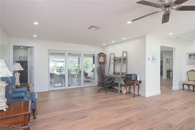 home office with light wood-type flooring and ceiling fan