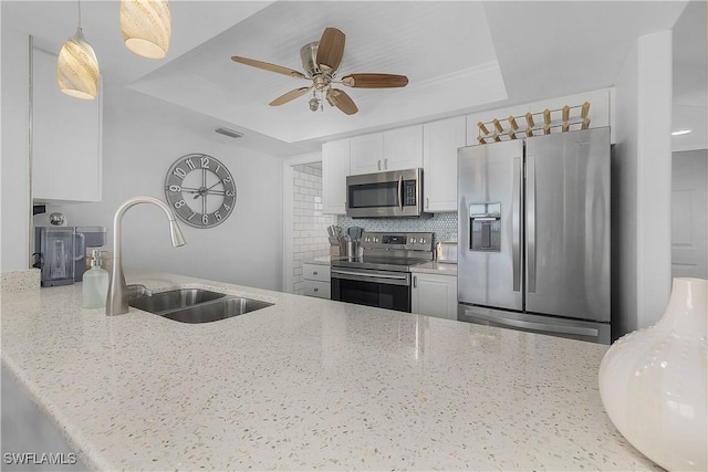 kitchen with white cabinets, appliances with stainless steel finishes, a raised ceiling, and light stone counters