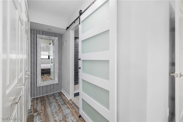 hallway with a barn door and dark hardwood / wood-style floors