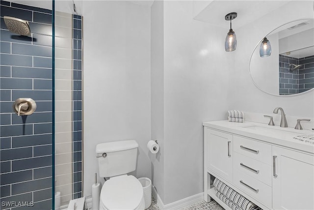 bathroom with tiled shower, vanity, and toilet