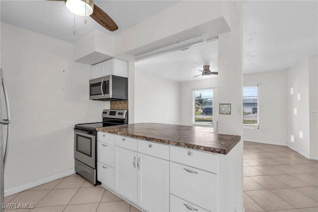 kitchen featuring stainless steel appliances, white cabinetry, light tile patterned floors, and backsplash