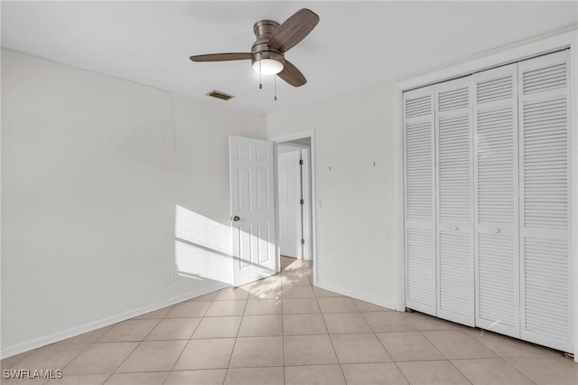 unfurnished bedroom with light tile patterned floors, ceiling fan, and a closet