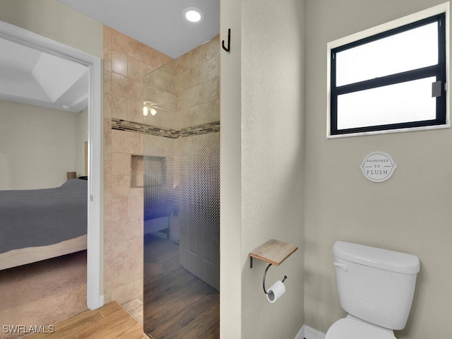 bathroom featuring ceiling fan, a shower, wood-type flooring, and toilet