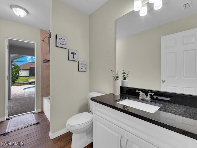 full bathroom featuring tiled shower / bath, vanity, and toilet