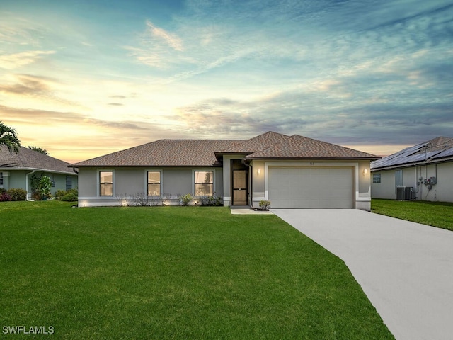 view of front facade with central air condition unit, a yard, and a garage