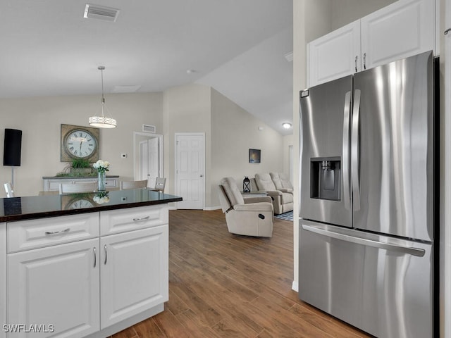 kitchen with stainless steel fridge with ice dispenser, vaulted ceiling, white cabinetry, and hardwood / wood-style floors