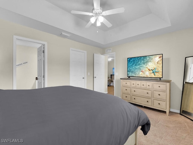 bedroom with a tray ceiling, ceiling fan, and light colored carpet