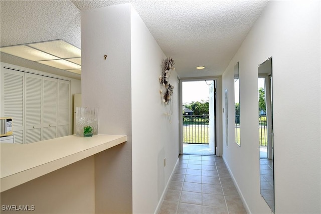 hall with light tile patterned floors and a textured ceiling