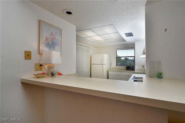 kitchen featuring kitchen peninsula, sink, and white fridge